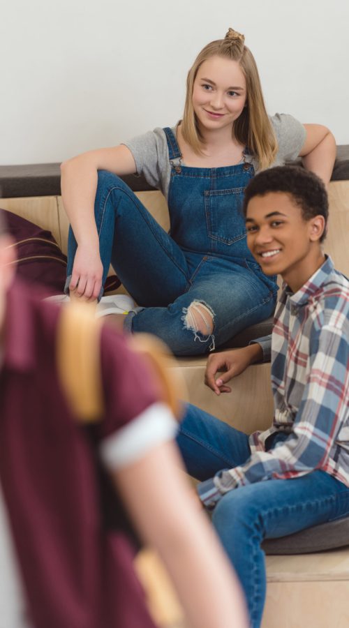 teenage students couple spending time together at school corridor